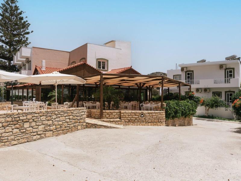 Buitengebied van een hotel met overdekte zitplekken en mediterrane architectuur.