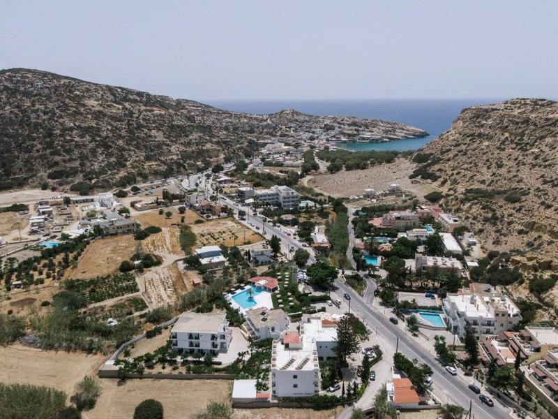 Uitzicht op een kustplaats met meerdere zwembaden tussen heuvels en blauwe zee op de achtergrond.