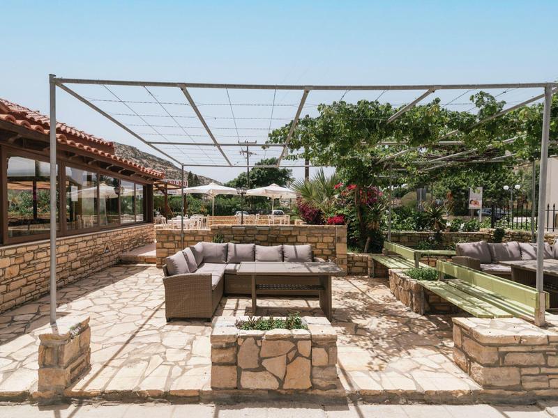 Ruim terras met gestoffeerde zitmeubels en pergola onder een heldere lucht.