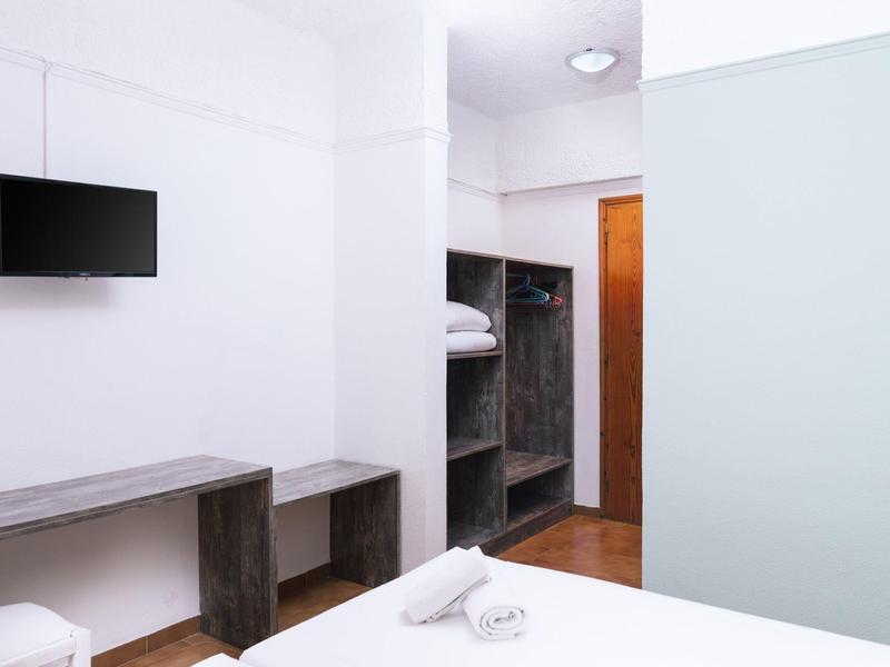 Moderne hotelkamer met tv, open kast en wit beddengoed.