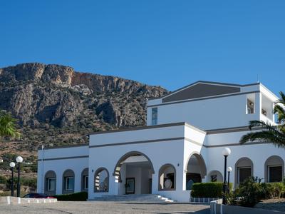 Edificio bianco moderno con finestre ad arco e montagne sullo sfondo in una giornata di sole.