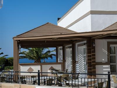 Terrazza coperta con sedie e vista sul mare in una giornata di sole.