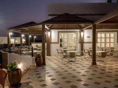 Terrazza dell'hotel illuminata con tavoli e sedie al crepuscolo.