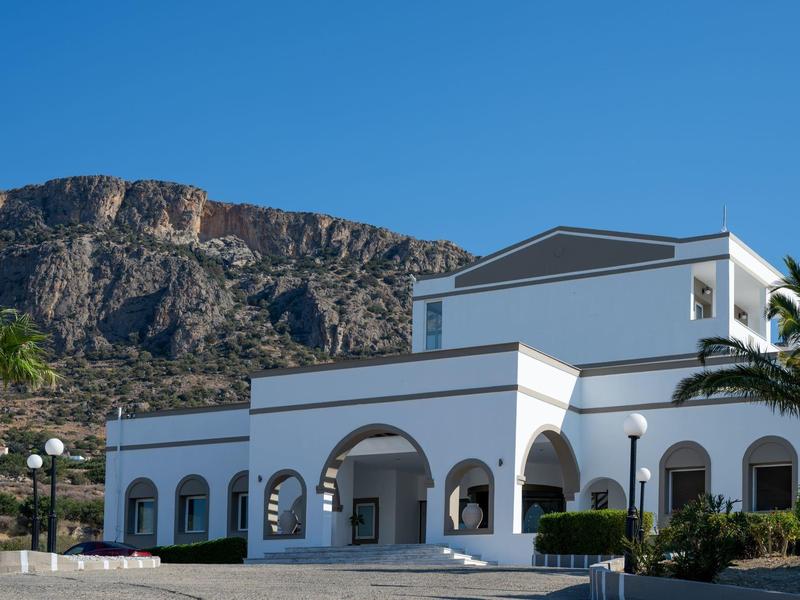 Edificio bianco moderno con finestre ad arco e montagne sullo sfondo in una giornata di sole.