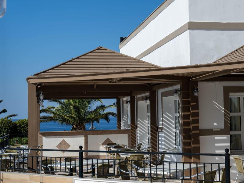 Terrazza dell'hotel con vista sul mare e palme sotto un cielo azzurro limpido