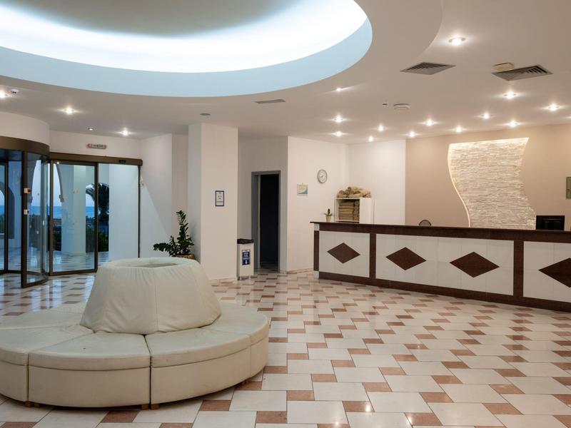 Lounge di hotel moderna con area salotto rotonda e reception rivestita in marmo.