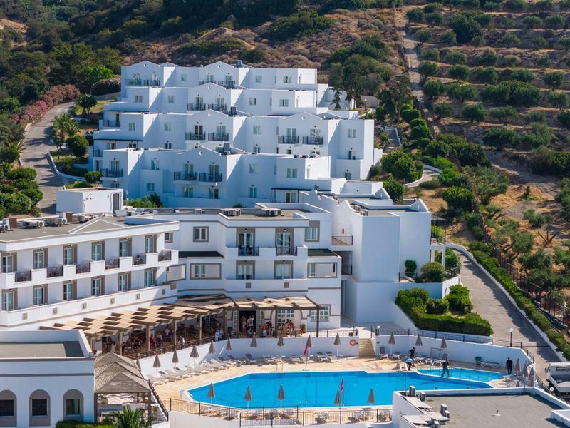 Complesso alberghiero con edificio bianco e piscina in paesaggio collinare