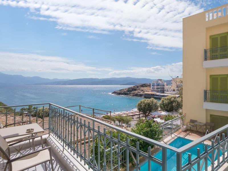 Balkon mit Sitzgelegenheiten und Blick auf das Meer und einen Pool neben einem Hotelgebäude.
