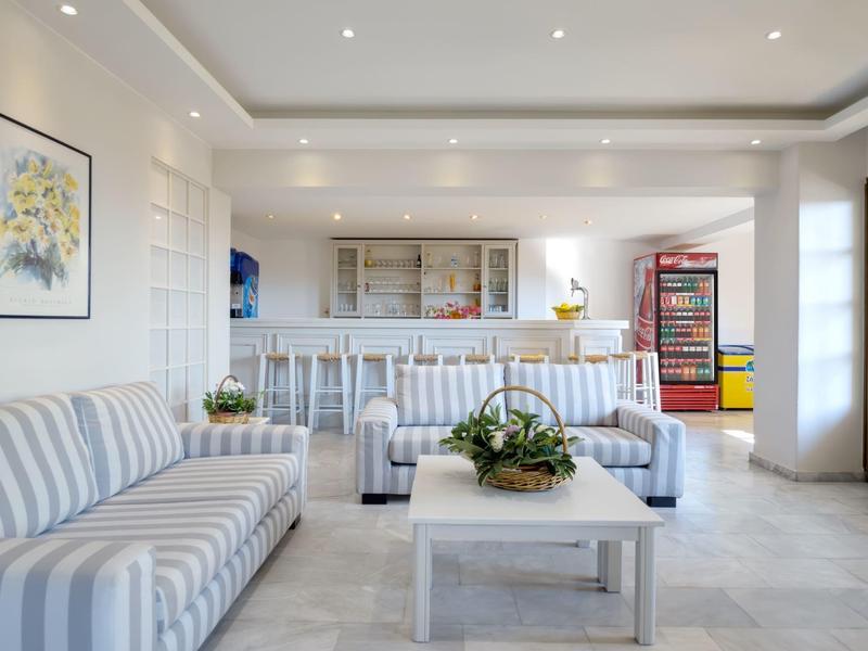 Helles, modernes Hotelzimmer mit gestreiften Sofas, weißem Tisch und Pflanze in der Mitte.