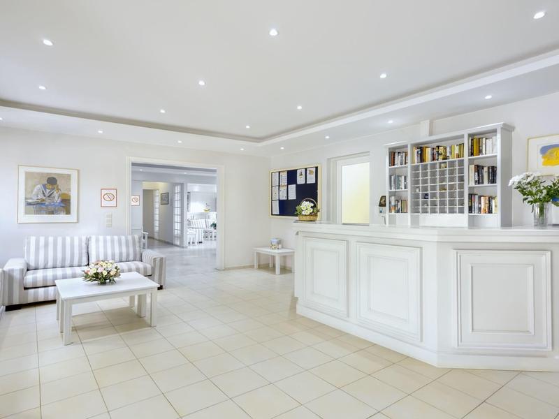 Heller Hotellobby mit weißem Empfangstresen, Sofas und moderner Beleuchtung.