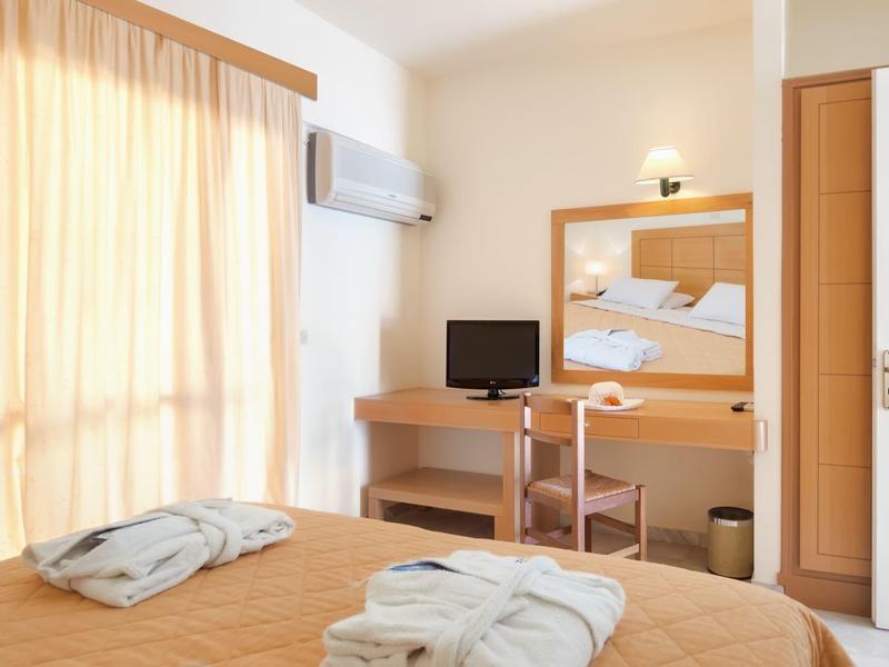 Helles Hotelzimmer mit Doppelbett, zwei Bademänteln, Schreibtisch und Fernseher.