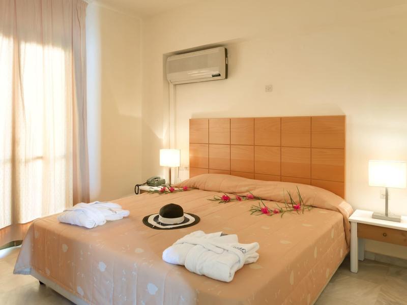 Helles Hotelzimmer mit Doppelbett, Nachttischlampen und Klimaanlage an der Wand