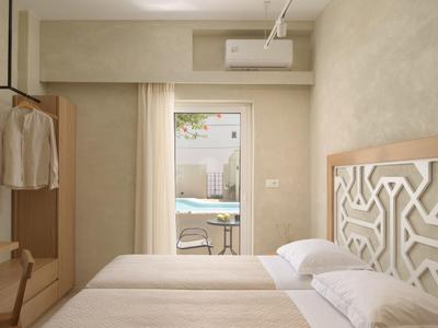 Jasny pokój hotelowy z dwoma łóżkami, stylową zagłówkiem i widokiem na basen.