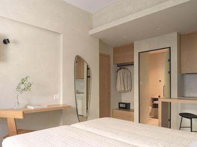 Nowoczesny pokój hotelowy z łóżkiem, biurkiem, dużym lustrem i otwartą szafą.