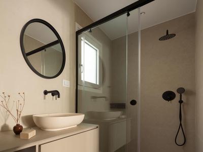 Nowoczesna łazienka z okrągłym lustrem, umywalką i prysznicem w ciepłych tonach