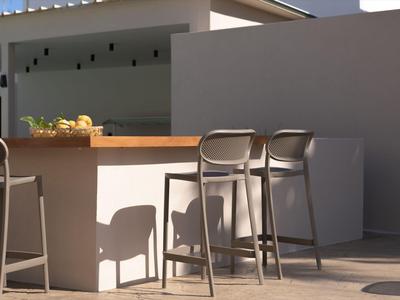 Nowoczesny bar na świeżym powietrzu z wysokimi krzesłami i prostym designem w słońcu.