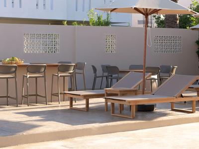 Nowoczesny basen z leżakami, parasolami i barem na zewnątrz.