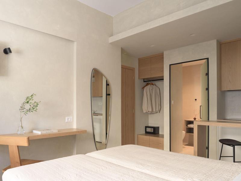 Nowoczesny pokój hotelowy z łóżkiem, biurkiem, dużym lustrem i otwartą szafą.