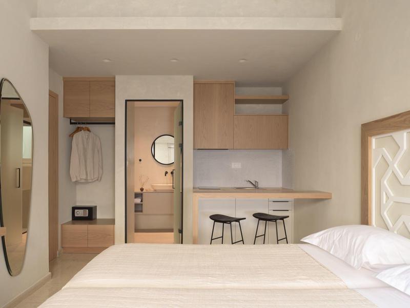 Nowoczesny pokój hotelowy z łóżkiem, okrągłymi lustrami i małym stołem z taboretami.