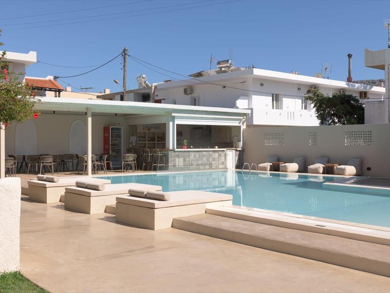 Nowoczesny basen z leżakami i zadaszonym miejscem do siedzenia pod bezchmurnym niebem.