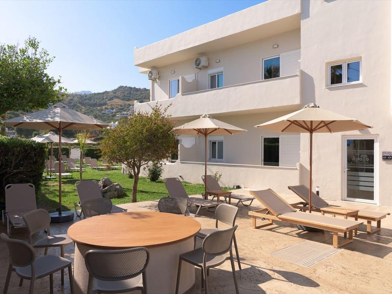 Taras z krzesłami, stołami i leżakami obok białego budynku hotelu pod czystym niebem.