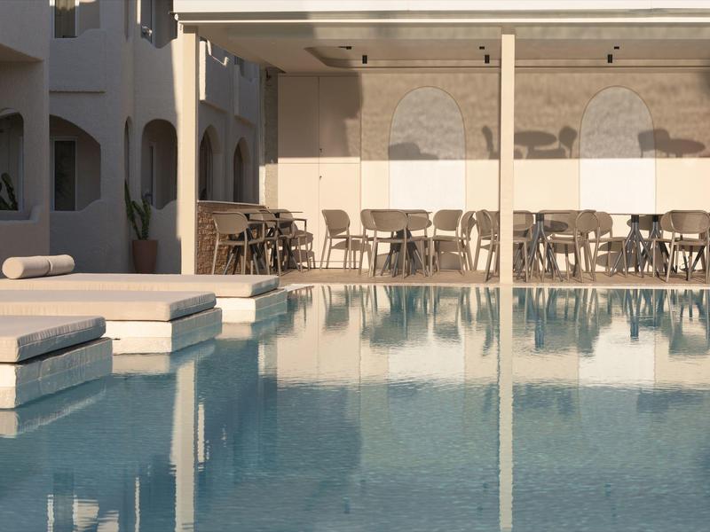 Nowoczesny basen hotelowy z leżakami i zadaszonym miejscem do siedzenia o zachodzie słońca.