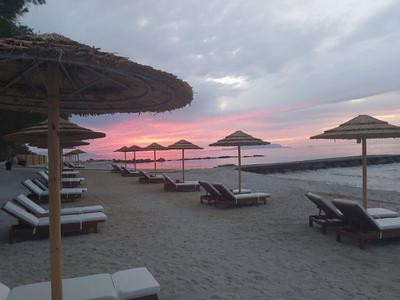 Beach with loungers and umbrellas at sunset by the sea.