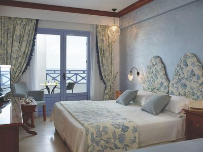 A cozy hotel room with double bed, floral design, and balcony with view.