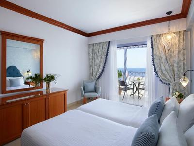 Bright hotel room with two single beds, balcony, and sea view.