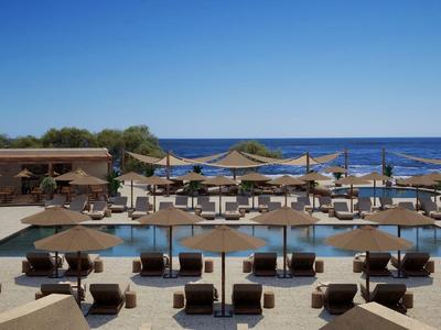 Piscine d'hôtel avec chaises longues et parasols au bord de la mer sous un ciel dégagé