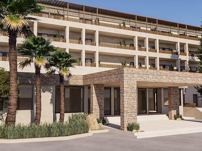 Hôtel moderne avec façade en grès, palmiers et plusieurs étages sous un ciel clair