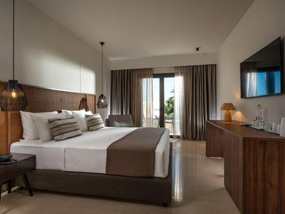 Chambre d'hôtel moderne avec lit double, mobilier en bois et balcon avec rideaux.