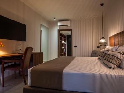 Chambre d'hôtel confortable avec grand lit, bureau, chaise et éclairage chaleureux.