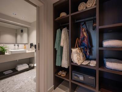 Moderner Hotelkleiderschrank mit Bademänteln, Schließfach und Blick auf ein Badezimmer mit Waschbecken.