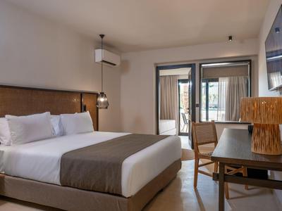 Modern eingerichtetes Hotelzimmer mit großem Bett, Schreibtisch und Zugang zu einem Balkon.