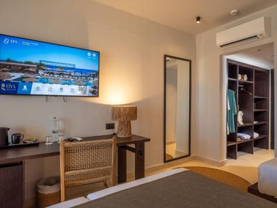 Modern eingerichtetes Hotelzimmer mit Fernseher, großem Spiegel und offenem Kleiderschrank.