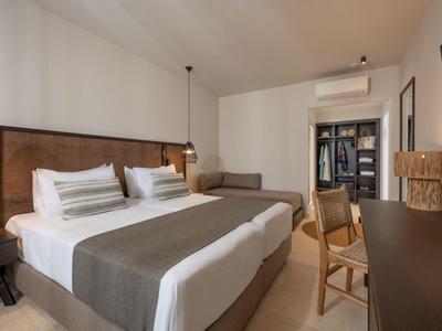 Modernes Hotelzimmer mit Doppelbett, Schreibtisch, Sitzbereich und neutraler Einrichtung.