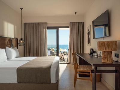 Modernes Hotelzimmer mit Doppelbett, Schreibtisch und Balkon mit Meerblick.