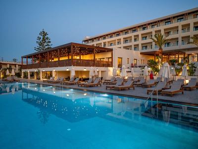 Modernes Hotel mit beleuchteter Bar und großem Pool am Abend.