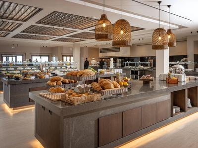 Buffetbereich in einem Hotel mit verschiedenen Backwaren auf dunklen Tischen und moderner Beleuchtung.