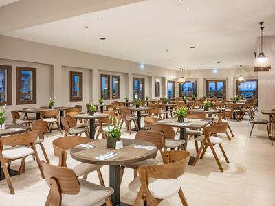 Großer heller Speisesaal mit Holzstühlen und Tischen, dekoriert mit Blumen.