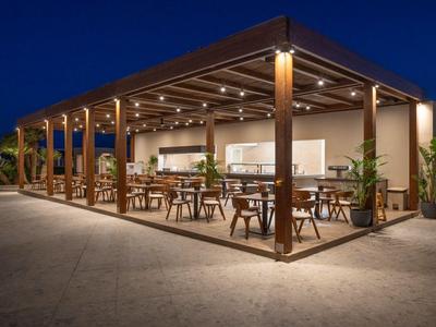 Modernes, offenes Restaurant mit Holzstruktur und Beleuchtung bei Nacht.