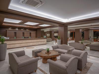 Elegante Hotellobby mit grauen Sesseln, Holztisch und moderner, indirekter Beleuchtung.