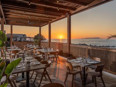 Offenes Restaurant auf der Terrasse mit Blick auf den Sonnenuntergang über dem Meer.