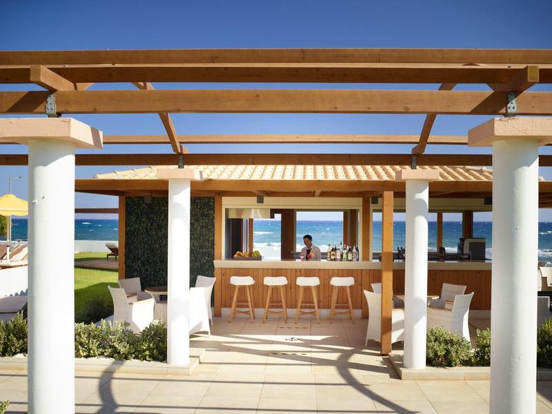 Open beach bar with wooden pergola and clear sky view of the sea.