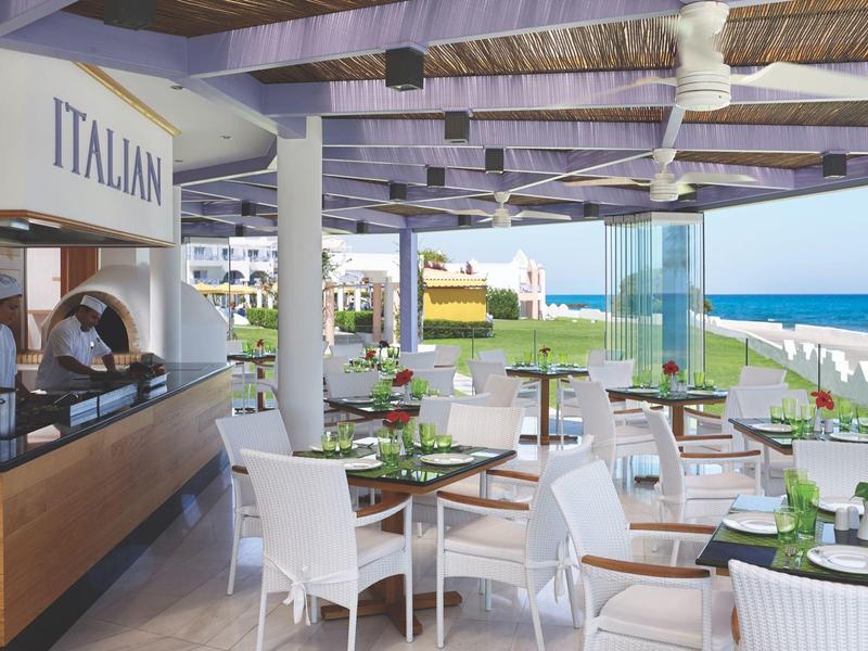 Terrace of an Italian restaurant overlooking the sea with seating area featuring white chairs.
