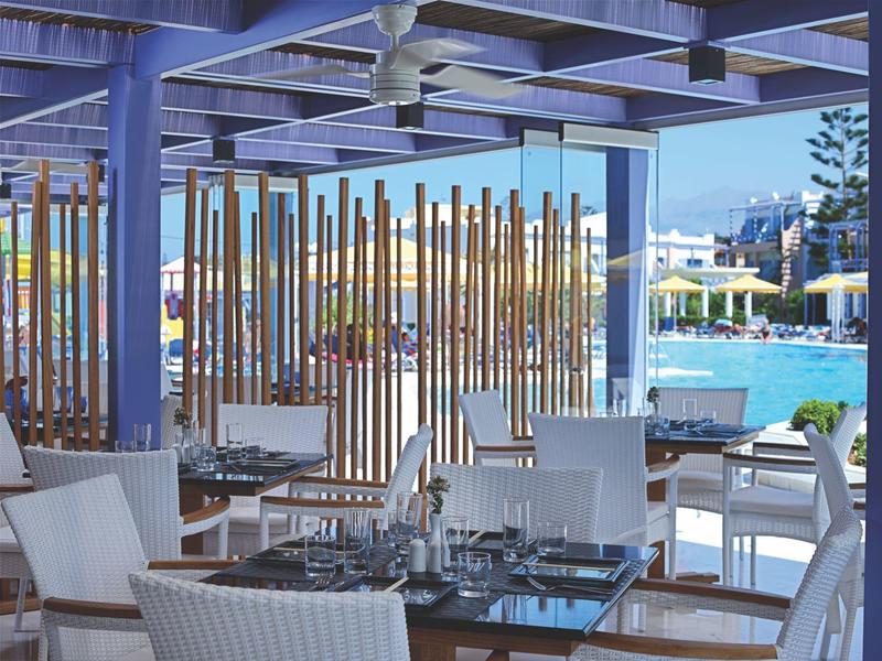 Modern hotel outdoor area with white chairs and a view of the pool.