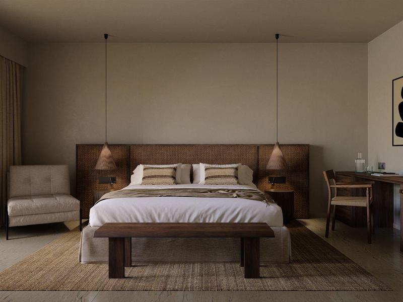 Modern furnished bedroom with large bed, armchairs, and desk in warm tones.