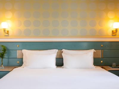 Moderne hotelkamer met een groot bed, twee witte kussens en sfeerverlichting.
