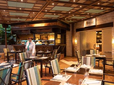 Gezellig hotelrestaurant met gedekte tafels en een informeel geklede ober.
